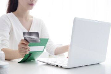 Young woman shopping online with credit card and bank book