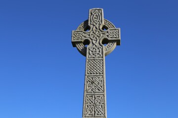 A closeup view of a Celtic Cross set against a bright, blue sky. 