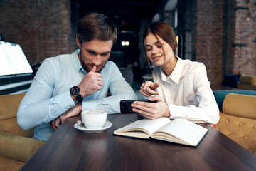 business man and woman sitting in a cafe having a snack rest communication telephone in hands