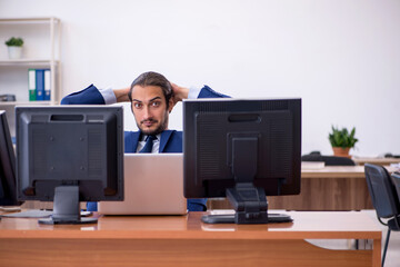 Young male employee in multitasking concept
