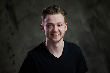Portrait of a cute caucasian guy with a smile on a gray background