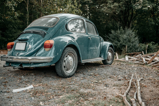 a green or blue vw beetle on a forest path.photo stylized as retro