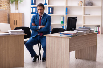 Young male employee in multitasking concept