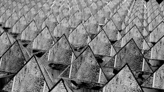 rotating rows of black and white pyramids with cracked texture. looped moving background. 3d render