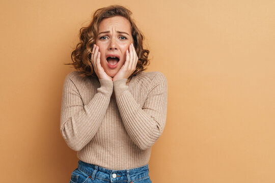 Young ginger scared woman frowning and screaming at camera