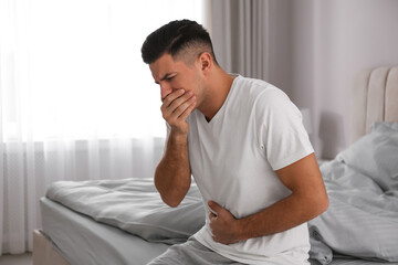 Man suffering from nausea on bed at home. Food poisoning - obrazy, fototapety, plakaty