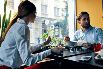a man and a woman in a shirt having dinner at a table in a restaurant interior in the background hot food drinks