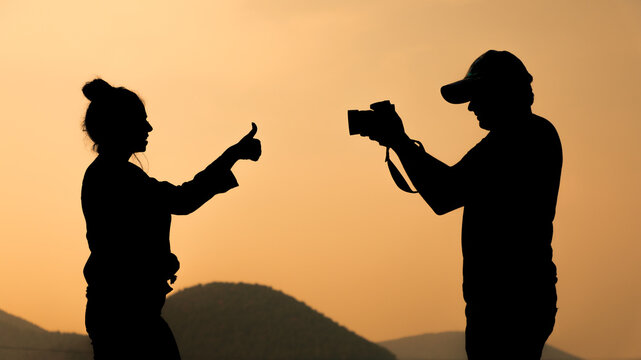 Silhouette of a cheerful couple clicking pictures from camera