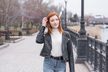 Fototapeta premium Portrait of a beautiful and positive redhead woman with clothes in grunge style. Posing while walking