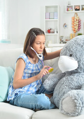  little girl  with stethoscope playing with  toy bear in facial mask