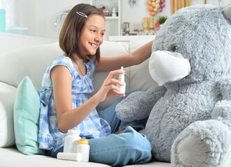  little girl  playing doctor with toy bear in facial mask