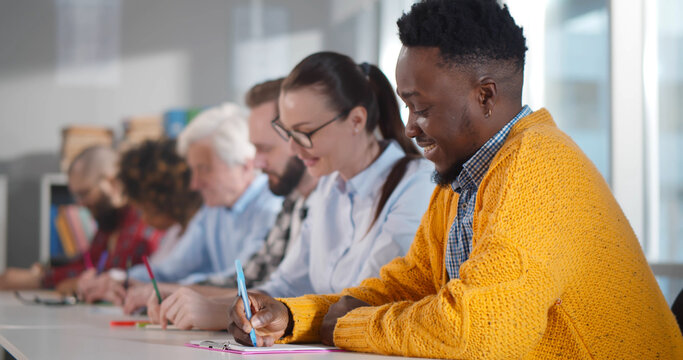 Multiethnic people sitting at desk and taking notes attending consulting seminar - Powered by Adobe