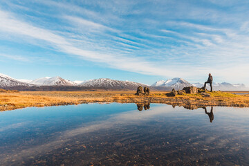 Man explorer in Iceland with his reflection on the water