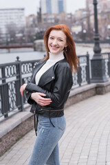 Fototapeta premium Portrait of a beautiful and positive redhead woman with clothes in grunge style. Posing while walking