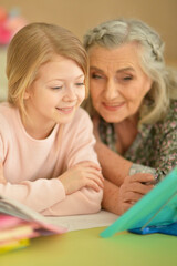 Fototapeta na wymiar Grandmother with cute little girl doing homework
