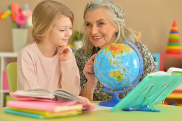 Grandmother with cute little girl doing homework