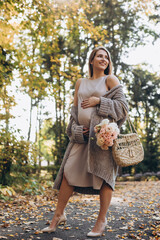 Beautiful pregnant woman walks in the green park. Summer park background.