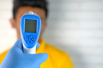 Hand holding infrared thermometer to measuring temperature of a patient 