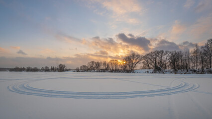 Winter sunrise over the frozen river and bare trees