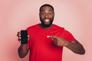 Young african man show point finger cellphone display isolated on pink background