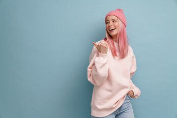 Young woman wearing pink hat laughing and pointing finger aside