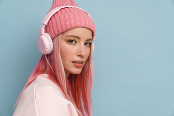 Young white woman wearing pink hat listening music with headphones