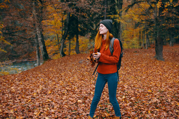 woman in a sweater hat jeans 3 law on the back and nature in the background trees forest model