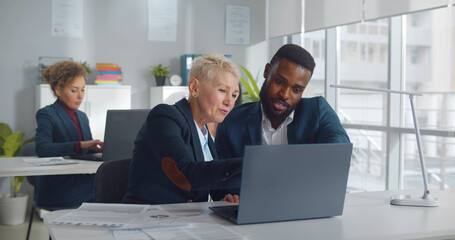 Diverse colleagues sitting at desk and discussing strategy of new startup project
