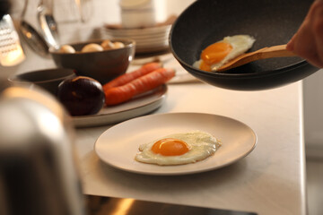 Man putting cooked eggs on plate from frying pan, closeup