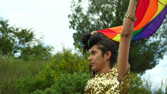 Mujer transgénero flameando la bandera LGTBQ mientras camina por el sendero 