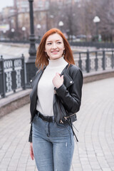 Portrait of a beautiful and positive redhead woman with clothes in grunge style. Posing while walking