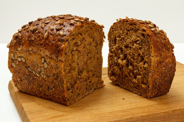 Cut loaf of bread on wooden cutting board on white background