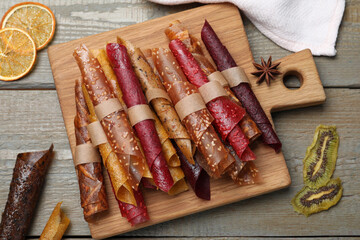 Delicious fruit leather rolls on wooden table, flat lay