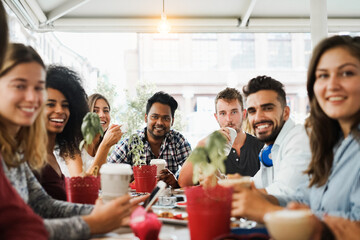 Young multiracial people eating brunch and drinking cappuccino at bar restaurant - Focus on center faces