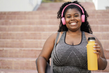Sport young african woman listening music with headphones after workout session - Focus on face