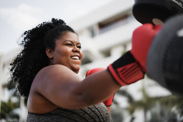 Curvy girl and personal trainer doing boxing workout session outdoor - Focus on face