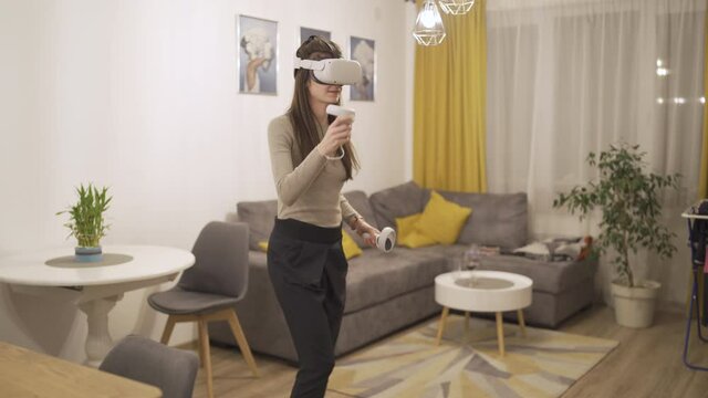 Smiling woman with VR headset playing games and fighting invisible objects using VR controllers