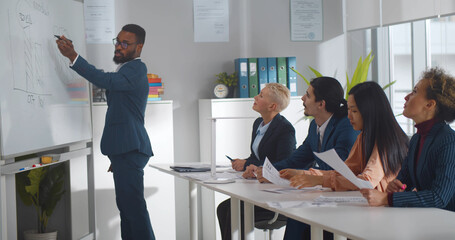 African american businessman giving at corporate meeting presenting project to colleagues