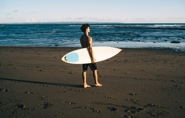 Fototapeta na wymiar Sportive man with surfboard walking on beach
