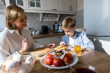 An adult woman in the kitchen looks like a child eats.