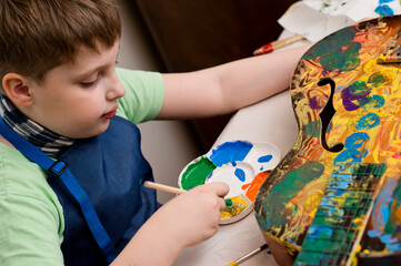 Kid have fun painting guitar. Color gouache art therapy lesion.