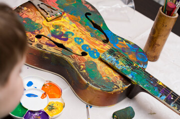 Kid have fun painting guitar. Color gouache art therapy lesion.