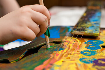 Kid have fun painting guitar. Color gouache art therapy lesion.