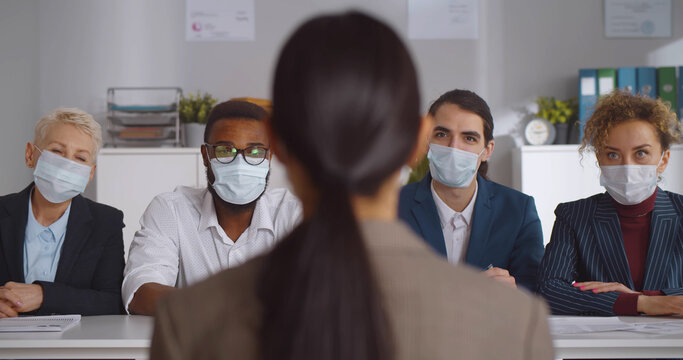 Executives wearing protective mask interviewing woman applicant