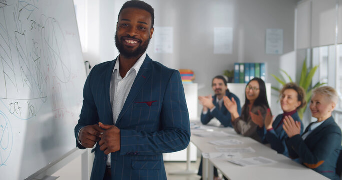 Afro-american businessman giving presentation using white board and smiling at camera