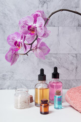 Bottles of tincture, salt, oil or serum, a towel and a blooming orchid in the bathroom. Skin care SPA concept
