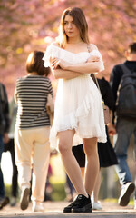 Young attractive woman in a white dress in the crowd on the street