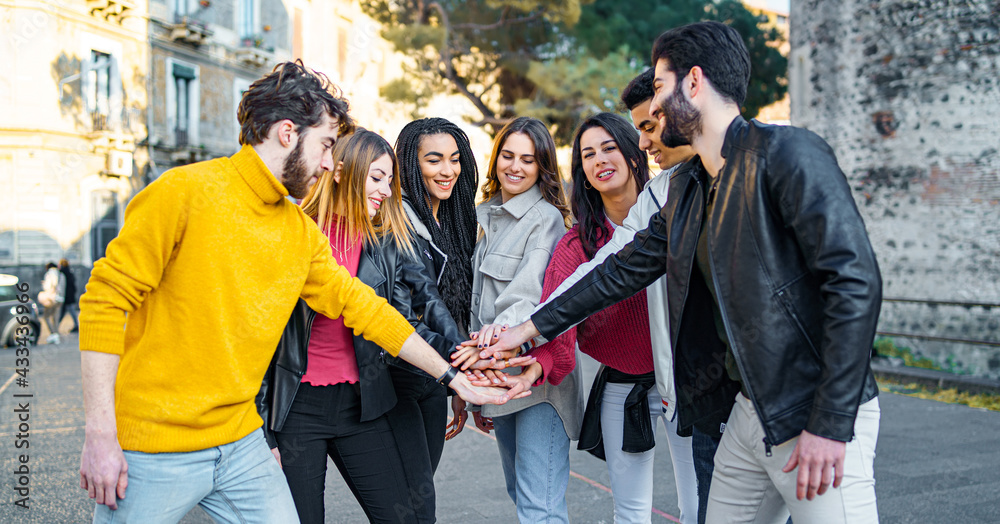 Wall mural group of multiracial young people joining hands - unity and trust concept