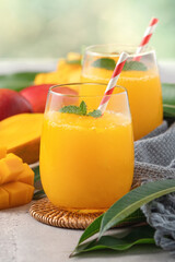 Fresh beautiful delicious mango juice smoothie in a glass cup on gray table background.