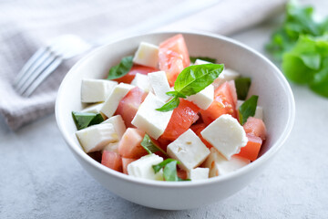 Italian caprese salad with sliced tomatoes, mozzarella, basil, olive oil on a light background. 